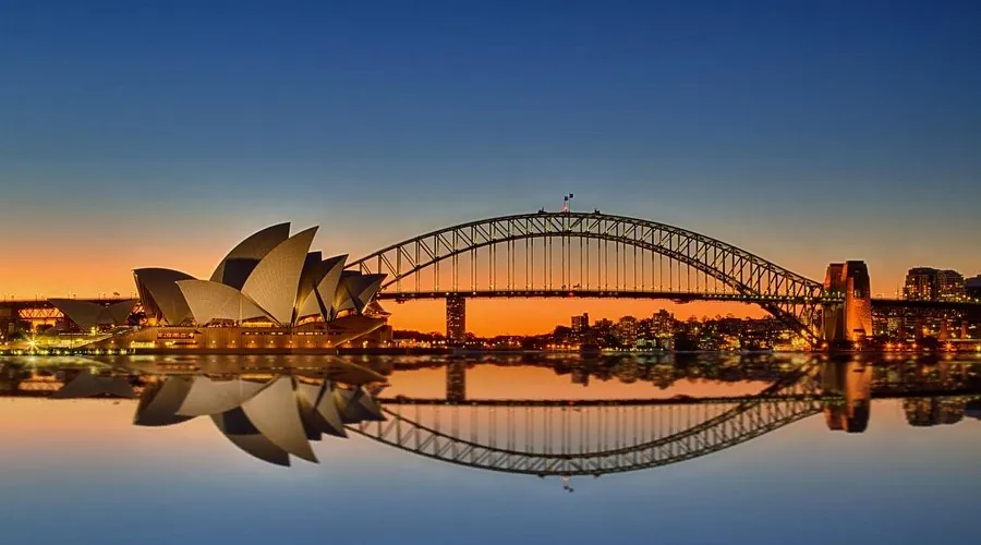 Sydney Opera House and Harbour Bridge reflected on the water at sunset