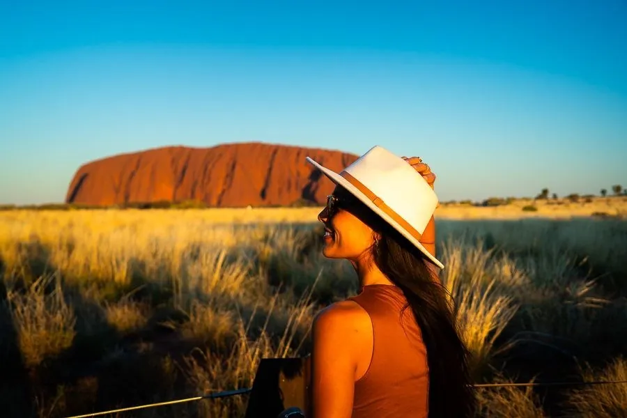 A woman taking in the view of Uluru at sunset