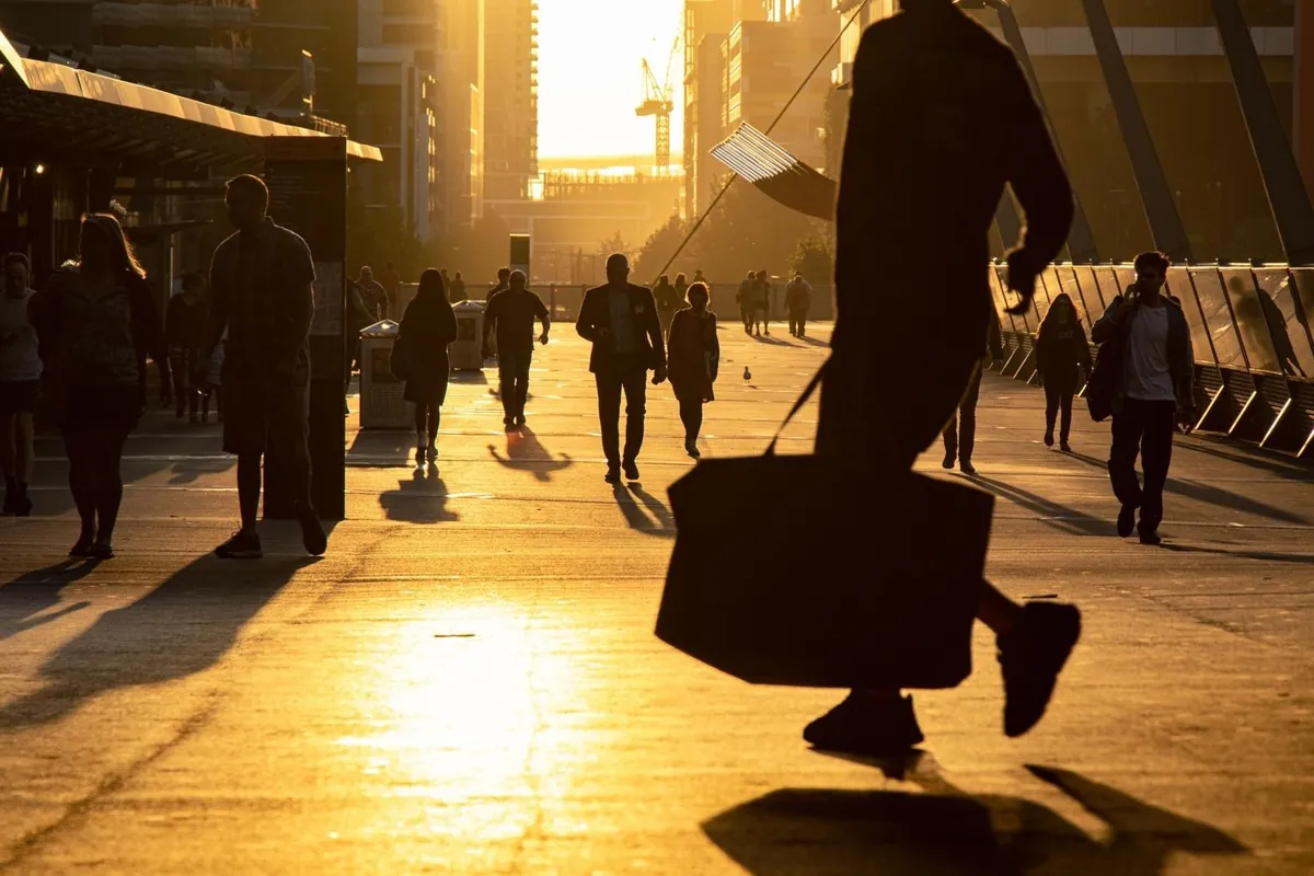 Silhouettes of people walking along a boardwalk at golden hour