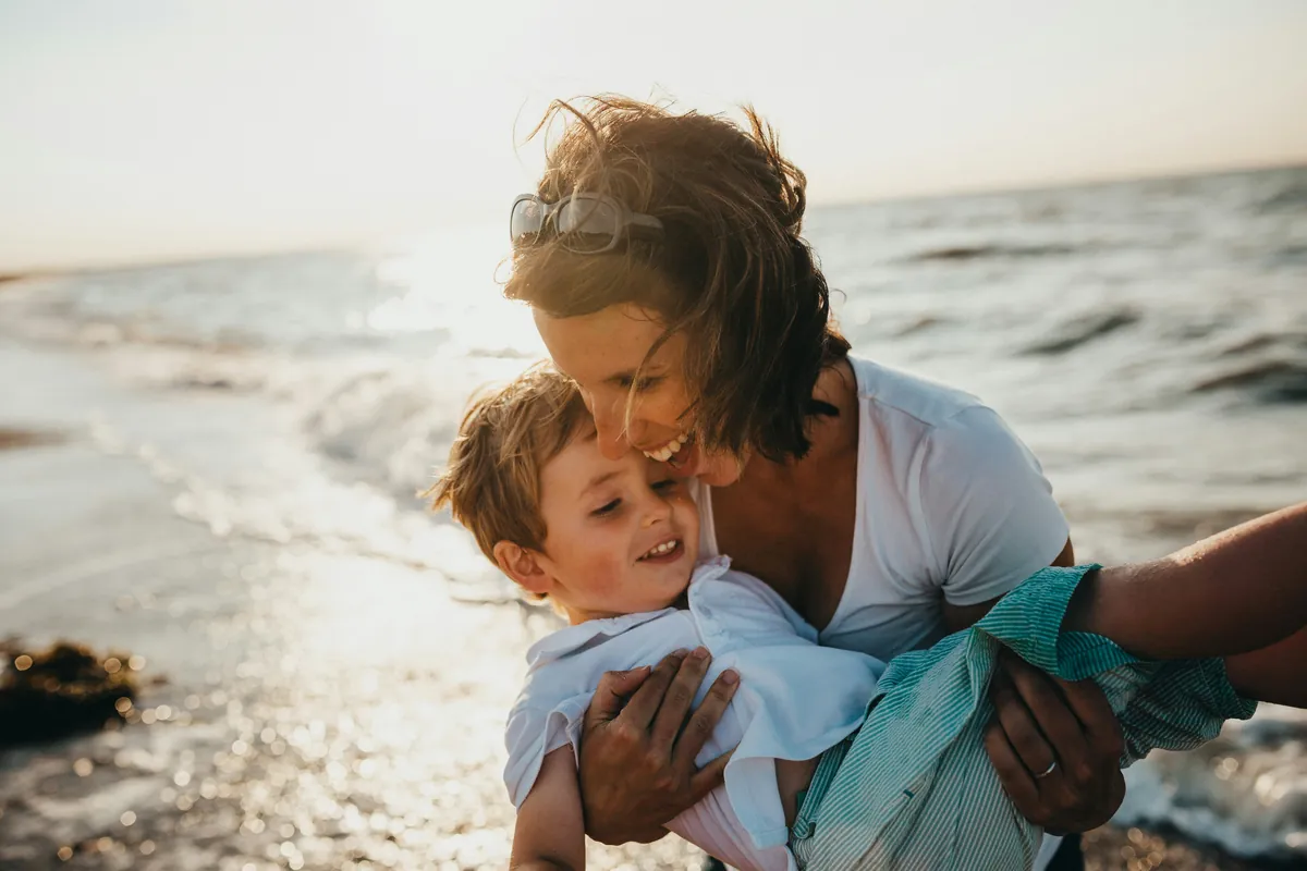 A mother laughing with her son on the beach