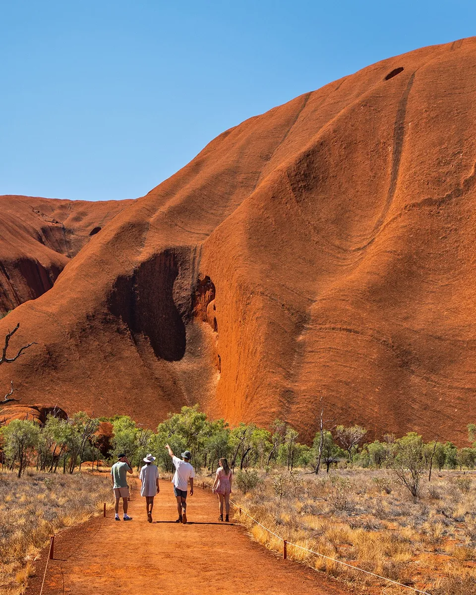 A family walking together on the path beneath Uluru