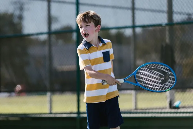 A young tennis player mid-swing on court