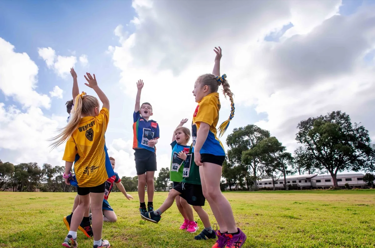 Young players leaping with their arms up at a sports carnival
